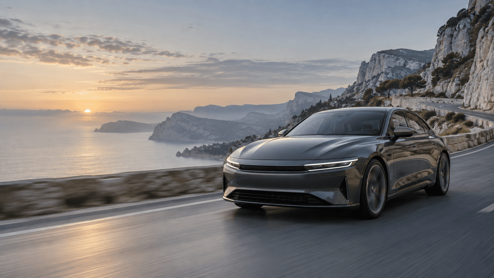 Graphite sedan driving on a coastal mountain road at dawn